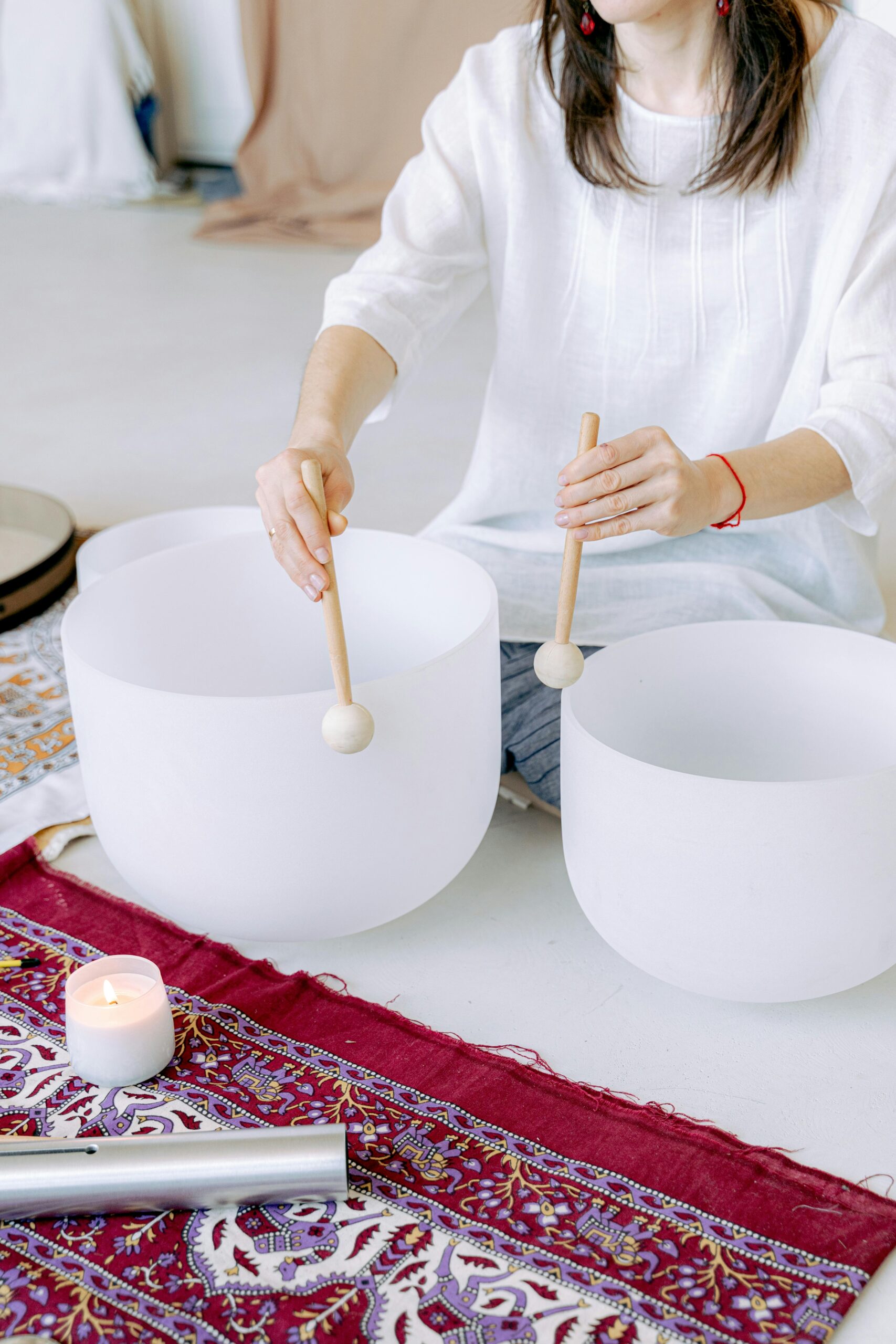 A woman playing crystal singing bowls during a meditation session for relaxation and well-being.