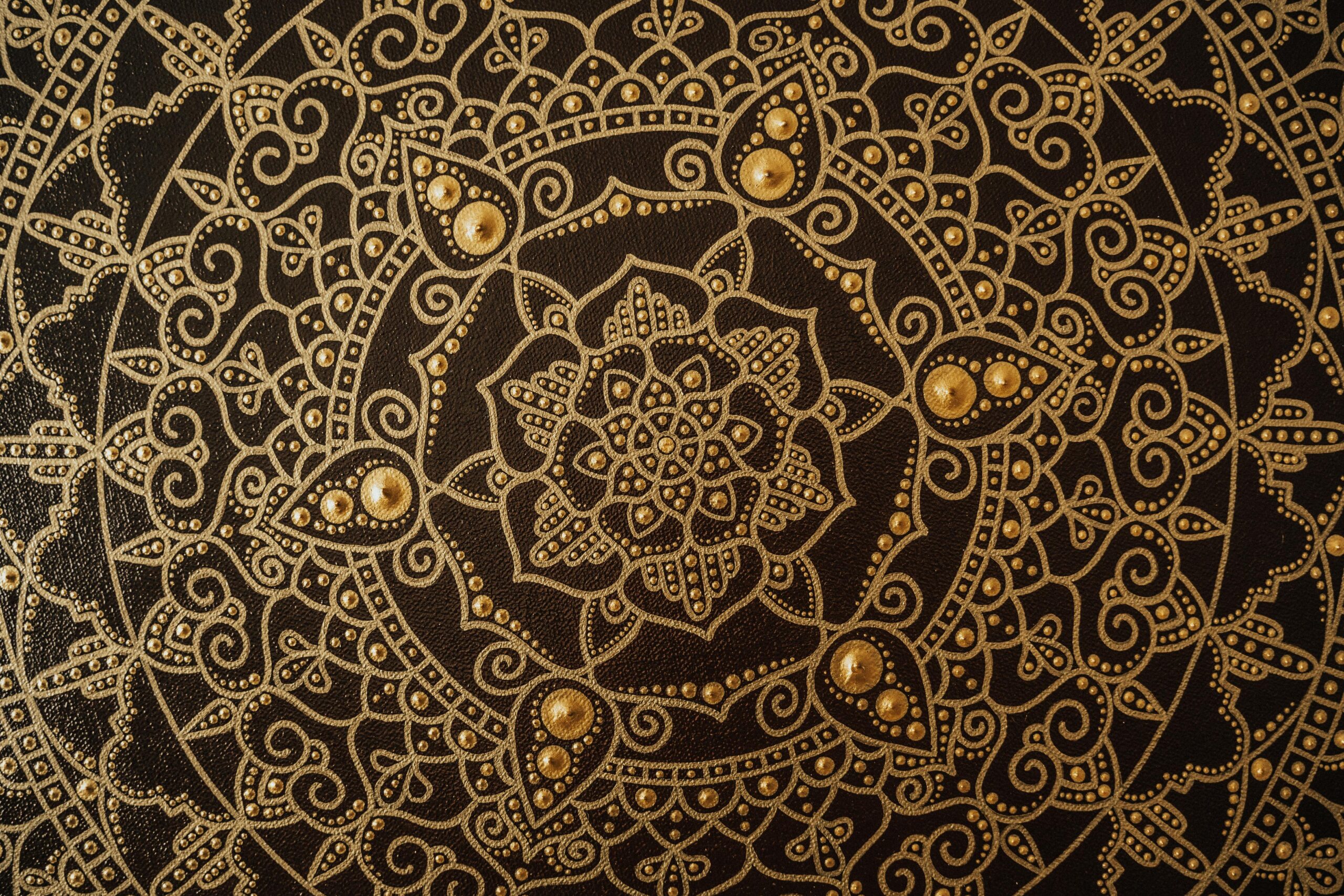 Close-up of an intricate gold mandala pattern on a dark canvas, showcasing detailed artistry.